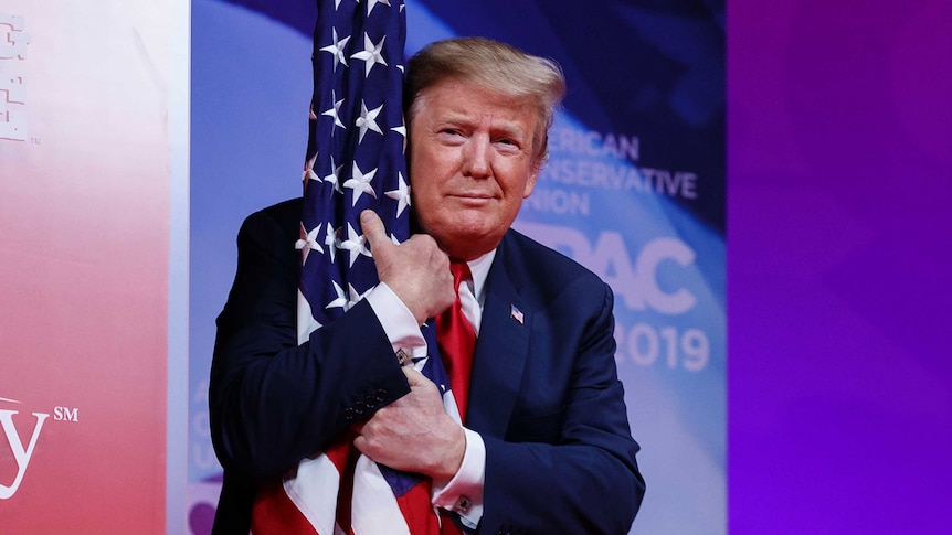Close up shot of Donald Trump hugging an American flag on a pole