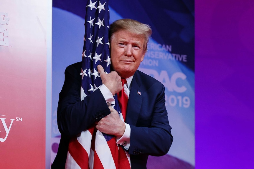 Close up shot of Donald Trump hugging an American flag on a pole