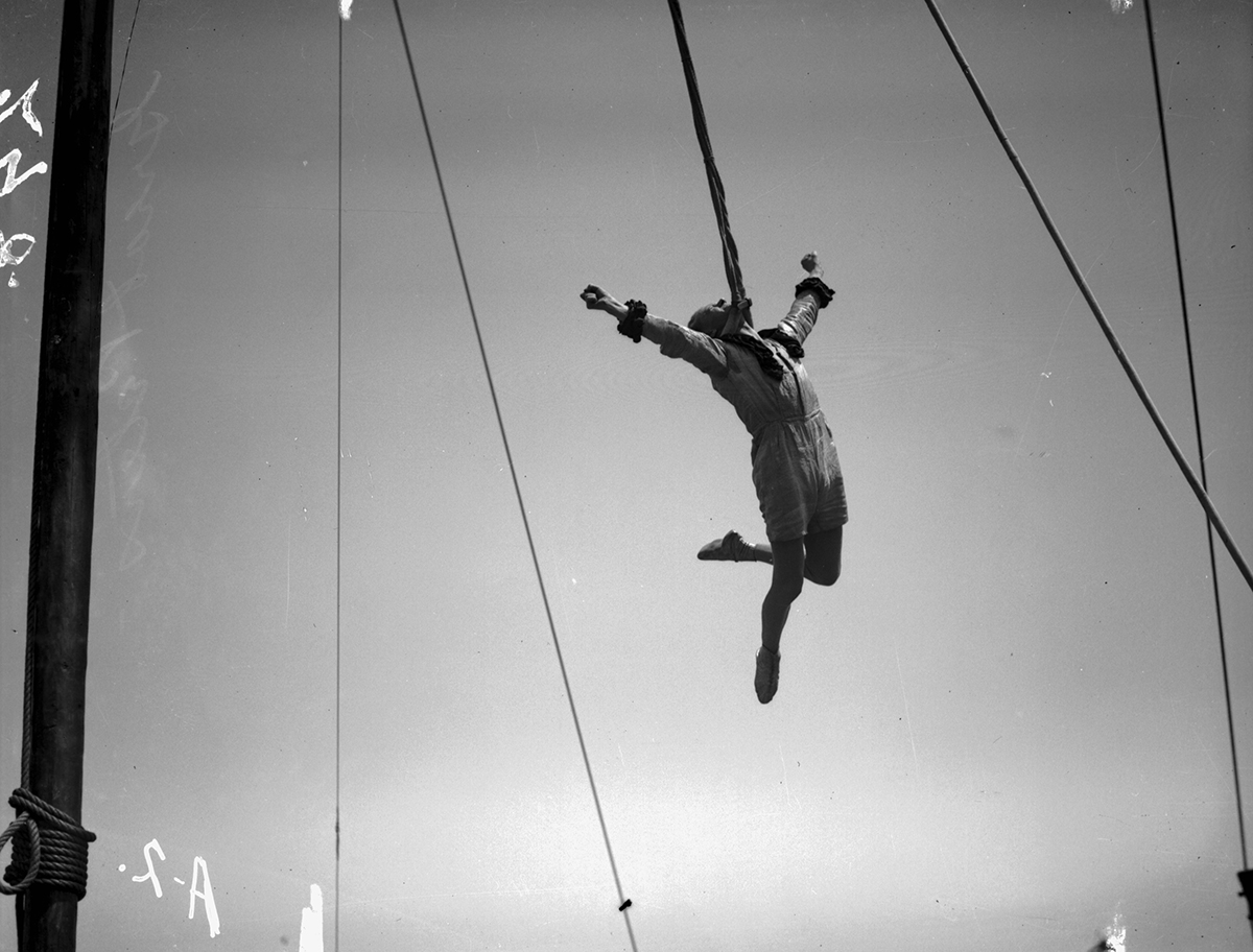Black and white glass plate negative of circus performer The Great Peters performing an aerial stunt in 1931.
