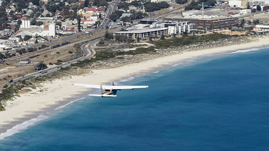 Plane flying along developed coastline.