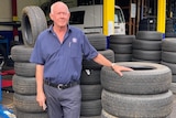A man standing next to a pile of tyres