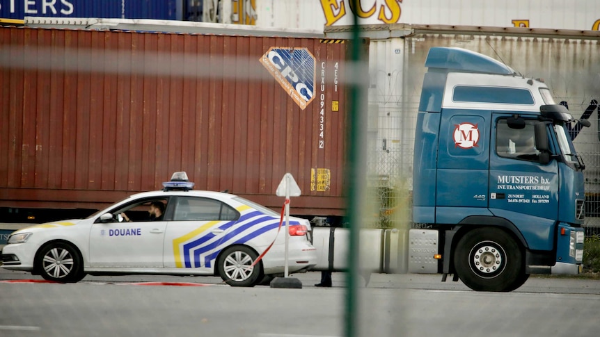 A police car next to a truck waiting to be scanned at the Port of Zeebrugge in Belgium