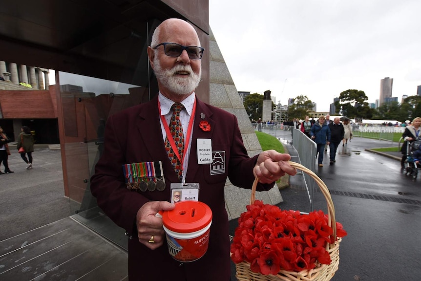 A man holds out poppies during a Melbourne Anzac Day ceremony