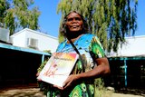 Alison 'Tjulapi' Carol holds a kids book called Tjulpu and Walpa