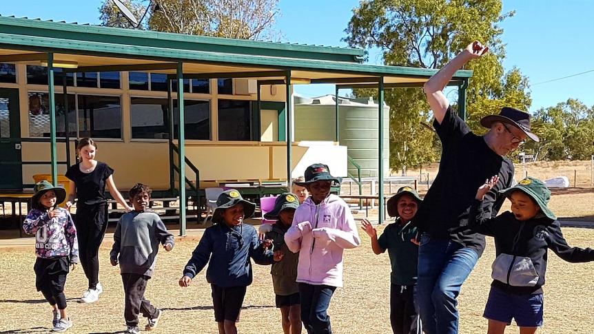 Amelie (far left) and Simon Storey running in the playground with around ten students from Dajarra school.