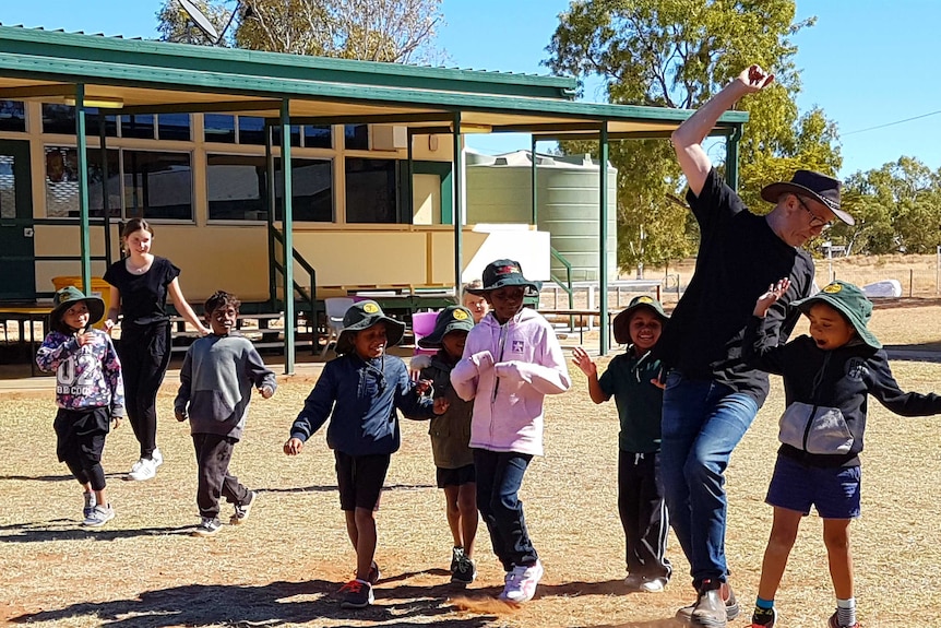 Amelie (far left) and Simon Storey running in the playground with around ten students from Dajarra school.
