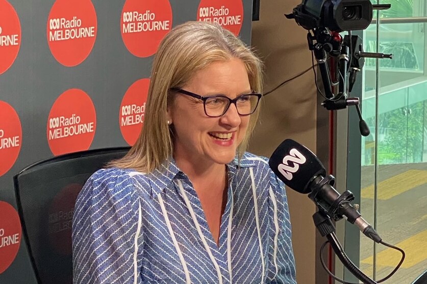 Jacinta Allan smiles, sitting in front of an ABC microphone.
