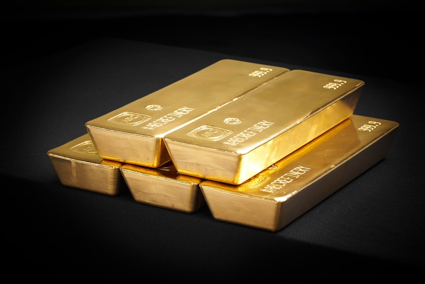 2 gold bars sit on 3 gold bars. Each has engraving on it with 999.9, a logo and an ID number