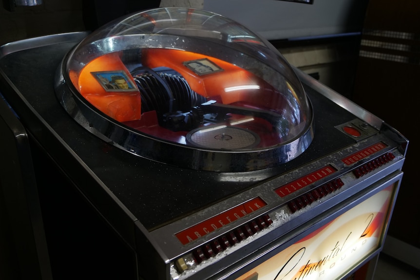 A glass dome with a record player in it, alongside a small picture of elvis presley.