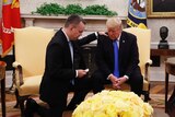 US Pastor Andrew Brunson kneels next to US President Donald Trump in the Oval Office