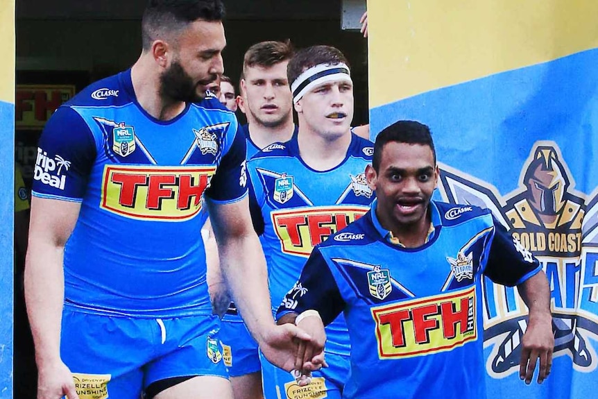 The captain of the Gold Coast Titans leads the team out on to the field accompanied by a smiling PDRL member Anno Pitt