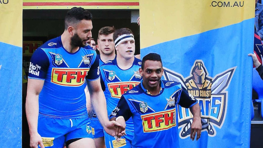 The captain of the Gold Coast Titans leads the team out on to the field accompanied by a smiling PDRL member Anno Pitt