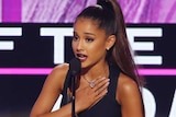 Pop star Ariana Grande accepts an award with her hand to her heart.