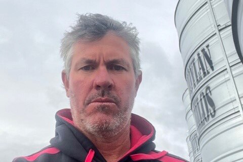 Selfie headshot of a man standing near grain silos