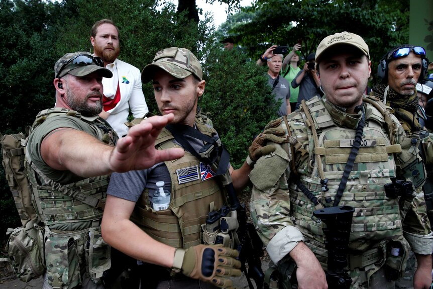 Armed militia members in camouflage block counter-protesters.