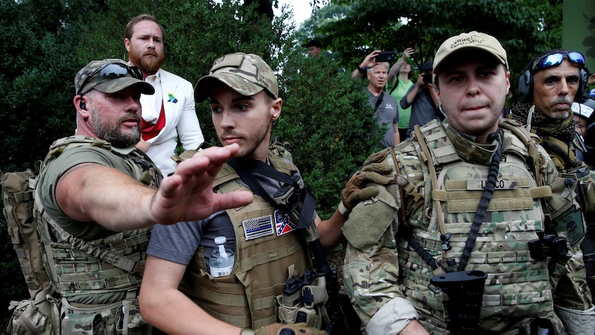 A white supremacist stands behind militia members after he scuffled with a counter demonstrator in Charlottesville, Virginia, U.S., August 12, 2017.