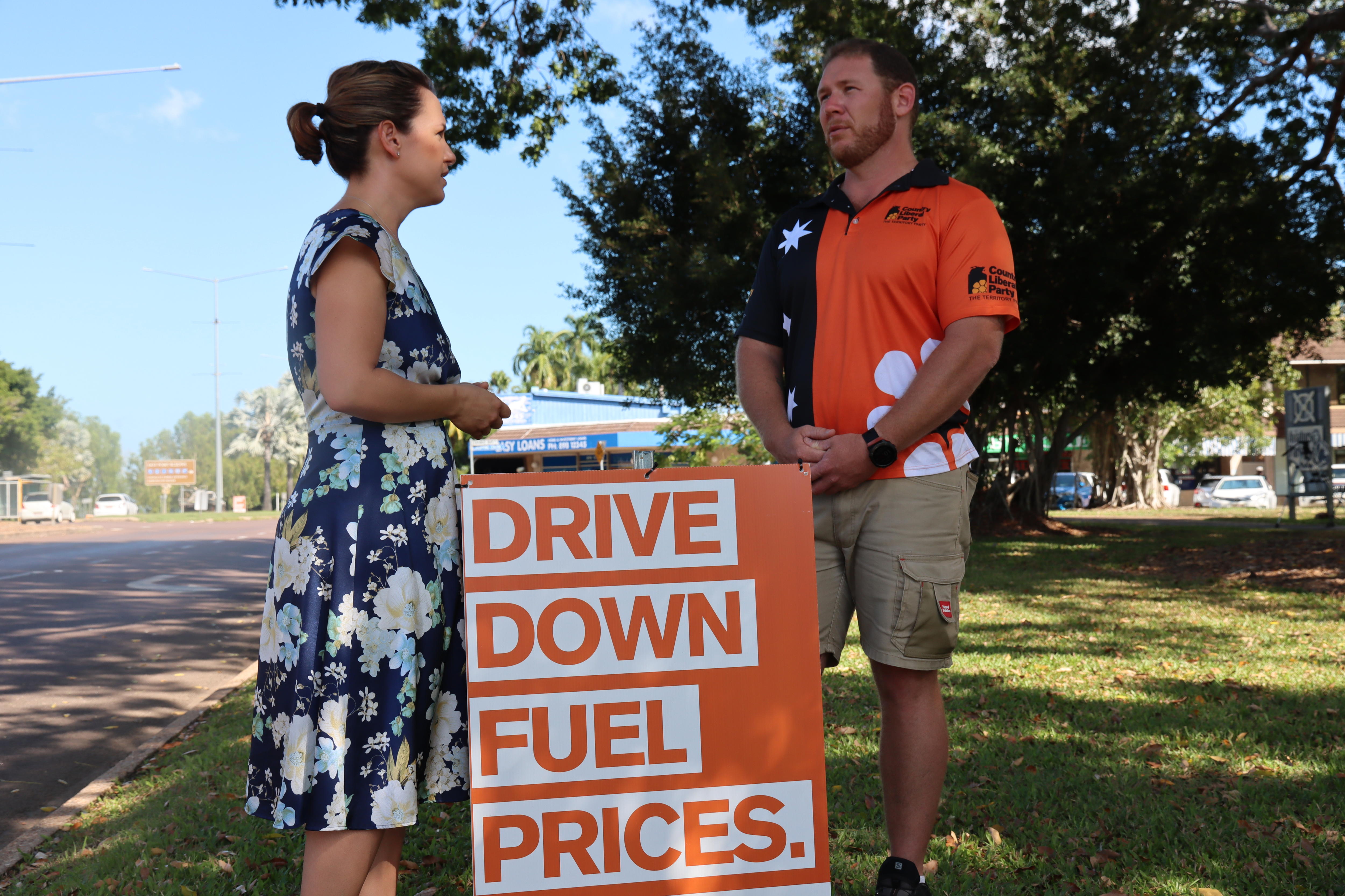 Lia Finocchiaro talking to Ben Hosking in front of a sign reading 'Drive Down Fuel Prices'