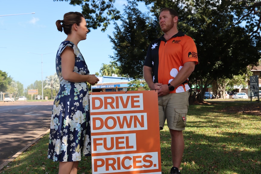 Lia Finocchiaro talking to Ben Hosking in front of a sign reading 'Drive Down Fuel Prices'