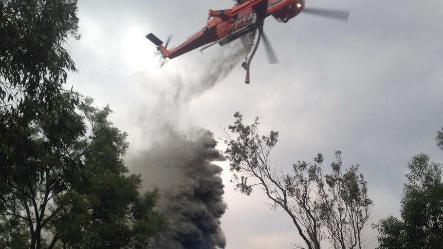 A large air crane dumps water on the blaze at Loxford.