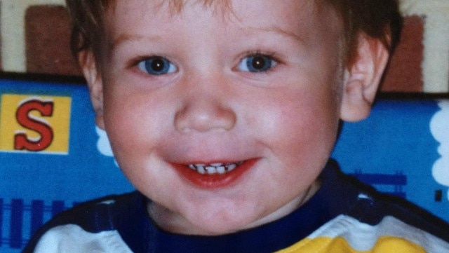 A family photo of a young boy with a colourful striped T-shirt.