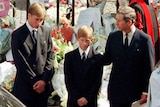 Prince Charles touches the shoulder of his son Harry as his other son Prince William watches the hearse bearing his mother Diana