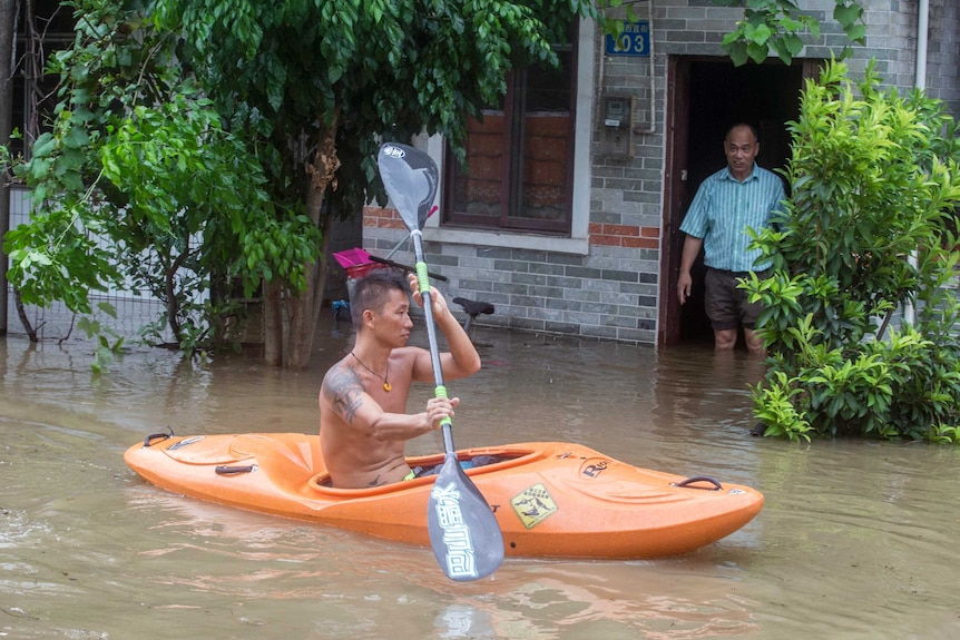 A man paddles a kayak along a flooded street caused by by Typhoon Hato in Guangzhou.
