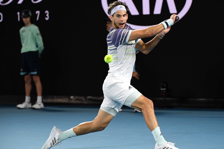 A male tennis player prepares to hit a backahdn behind the baseline at the Australian Open.