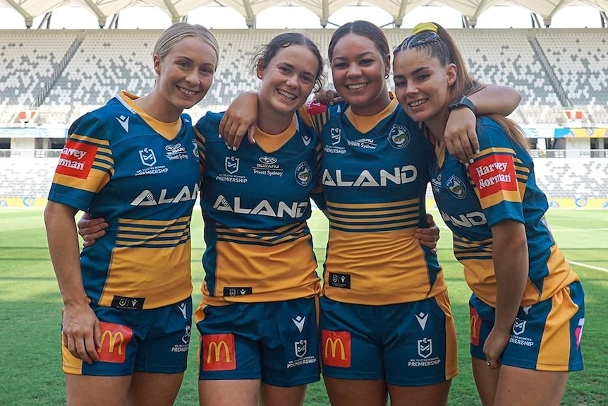 Abbi Church, Tess Staines, Kennedy Cherrington et Katrina Phippen se tiennent bras dessus bras dessous dans les maillots Parramatta Eels NRLW.