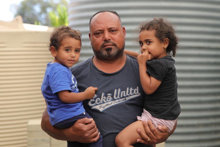 A man holds two young children in each arm