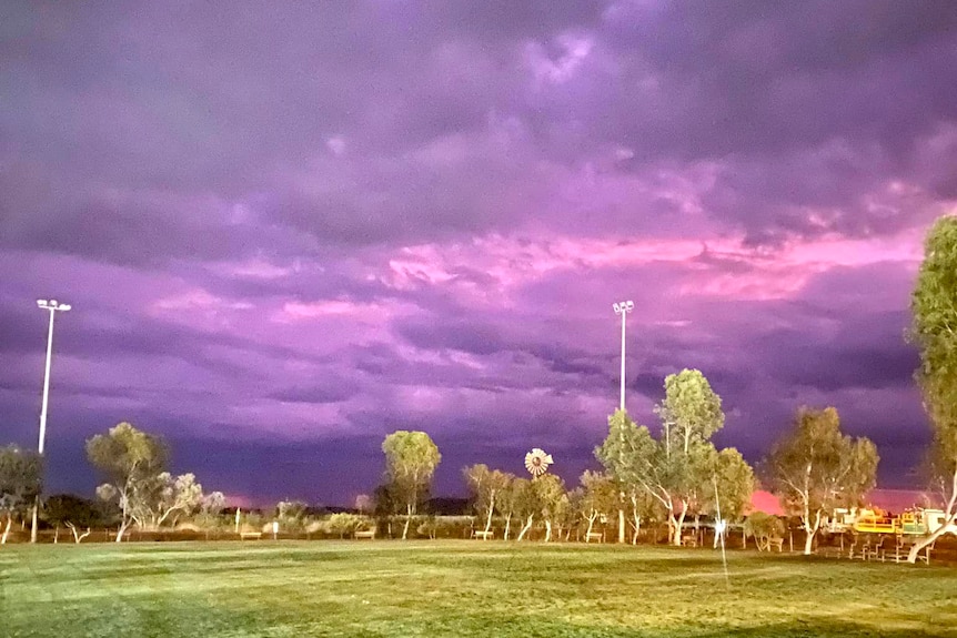 A sports oval at night with dramatic purple skies overhead.