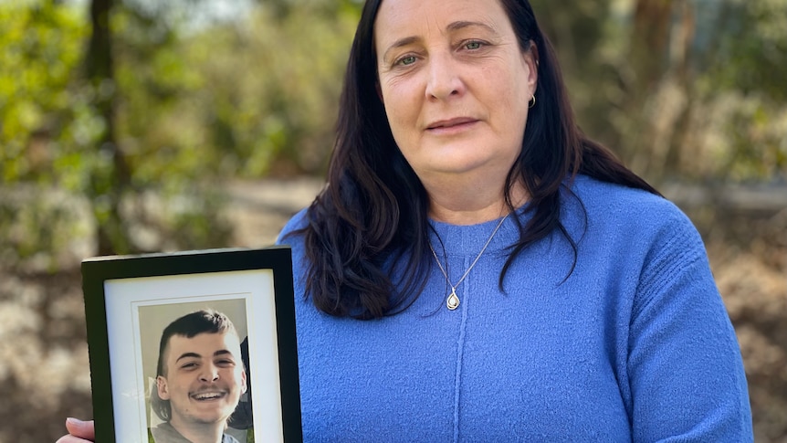 Nicole Hammat holds a framed photograph of her son Khye smiling 