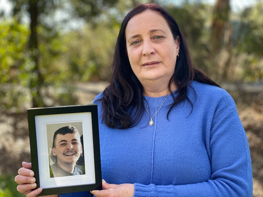 Nicole Hammat holds a framed photograph of her son Khye smiling 
