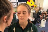 Students apply make-up to each other