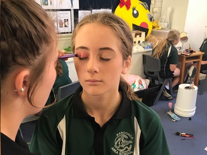 students applying make up to each other