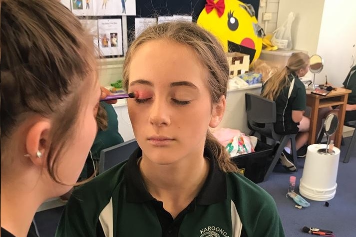 Students apply make-up to each other