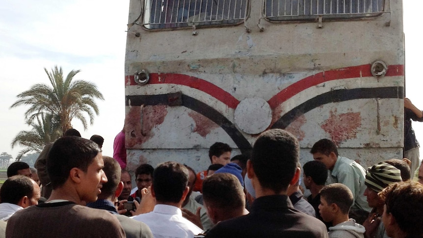 Relatives of victims gather near a blood-stained train after it crashed into a school bus