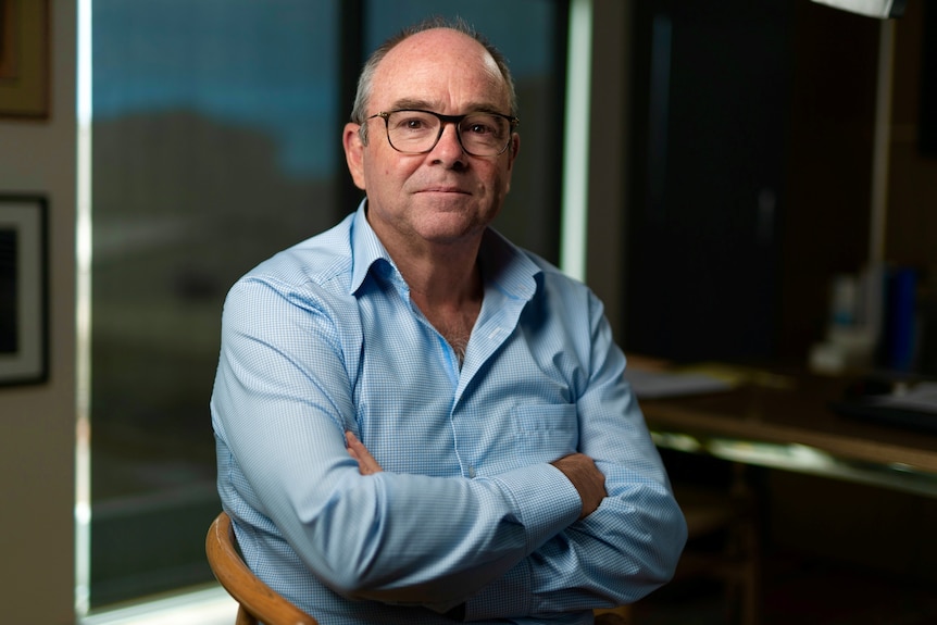 Man wearing glasses and light blue shirt with his arms folded.