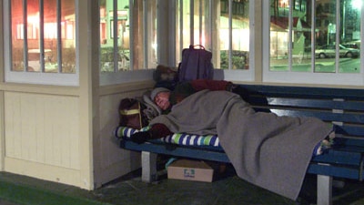 A homeless man sleeps in a bus shelter. (File photo)