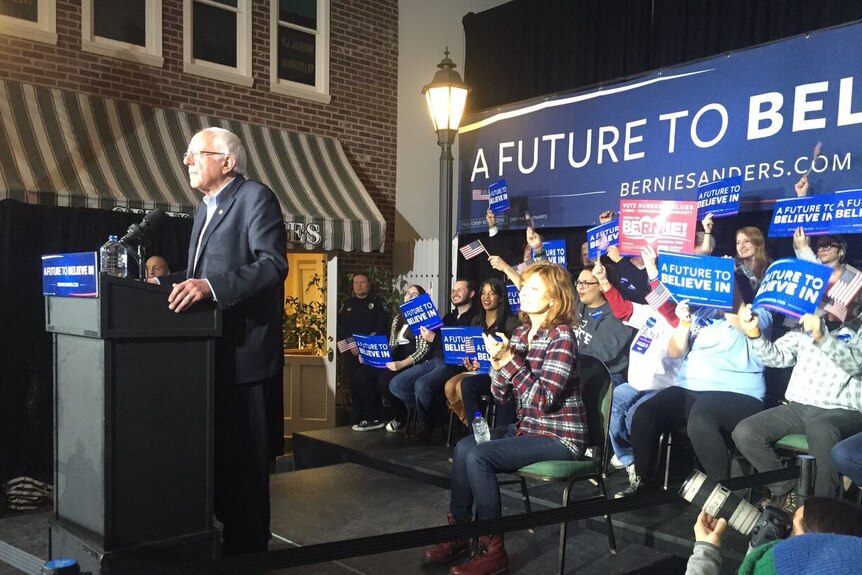 Bernie Sanders, flanked by his supporters, speaks at an event in Iowa.