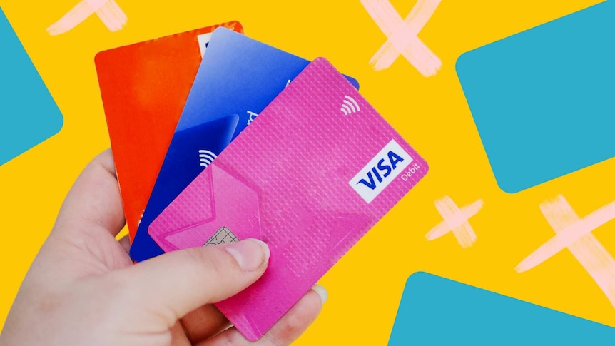 A person holds three debit cards for a story about why you don't need a credit card, plus tips for getting rid of one.