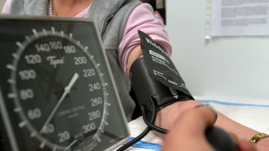 a woman with her arm out getting  blood pressure tested