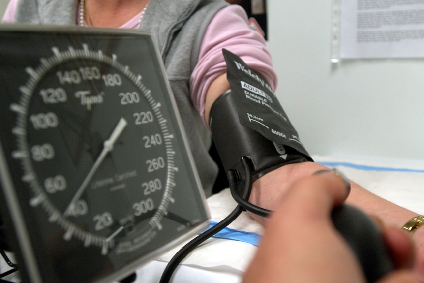 a woman with her arm out getting  blood pressure tested