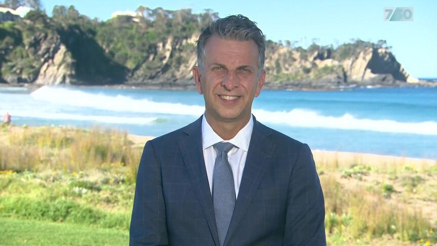 Andrew Constance talks to media in front of picturesque beach