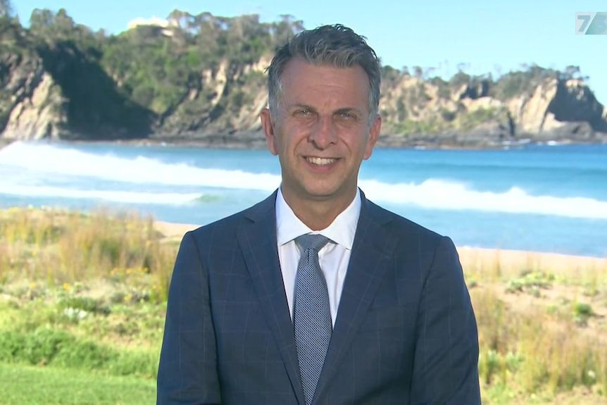 Andrew Constance talks to media in front of picturesque beach