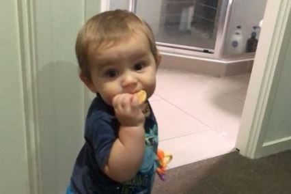 Toddler Jaylen Troy Priest looks up while eating a biscuit.
