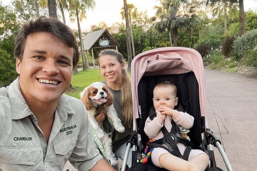 An image of bindi irwin with husband chandler and their child Grace in a pram