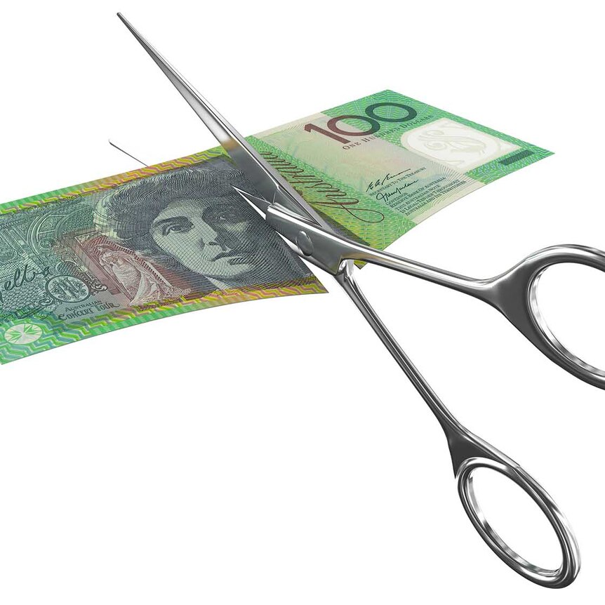 Scissors cutting through a $100 Australian bill 