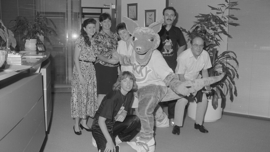 A group of people pose for a photo, with a kangaroo costume in the middle.
