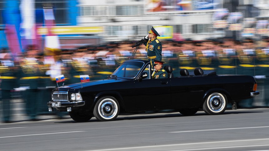 Major-General Yakov Rezantsev salutes while standing in the back of a car during the Victory Day parade.