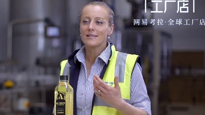 A woman holding a bottle of canola oil presenting to camera